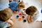 Excited little toddler girl and two kids boys coloring eggs for Easter. Three children, siblings looking surprised at