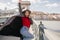 Excited long-haired woman dancing in long coat and laughing on urban background. Slim girl in red sweater spending