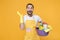 Excited man househusband in apron rubber gloves hold basin detergent bottles washing cleansers doing housework isolated