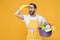 Excited man househusband in apron rubber gloves hold basin detergent bottles washing cleansers isolated on yellow