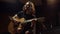 Excited man playing guitar in music studio. Cheerful guy singing in dark hall.