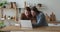 Excited millennial couple using laptop at kitchen table, chatting