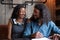 Excited mixed race married couple signing paper contract in cafe