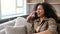 Excited multiracial young woman taking emotional on the smartphone sitting on the sofa at home