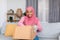 Excited muslim woman opening cardboard box, receiving online store order, satisfied with good delivery service