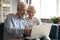 Excited older couple reading good news, using laptop together