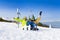 Excited parents and kid in ski masks sit on snow