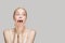Excited shocked woman with healthy clear fresh skin against grey studio wall banner white background
