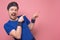 Excited sportive young man in blue t-shirt and hair band cheering and pointing on copyspace