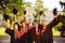 Excited successful happy five graduates in robes together rise mortar-board with tassel