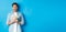 Excited and surprised attractive man, holding money prize and smiling amazed, standing over blue background