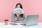 Excited surprised woman office worker holding and peeking out of hundreds dollar banknotes sitting at workplace with laptop,