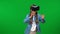 Excited teen Caucasian girl gaming online in VR goggles turning at green screen background. Absorbed happy teenage gamer