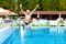 Excited teenage boy jumping in the pool