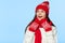 Excited woman looking sideways in excitement. Surprised christmas girl wearing knitted warm hat and scarf, isolated on blue