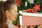 Excited woman near Christmas tree looking inside Christmas gift