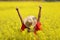 Excited woman with pamela raising arms in a yellow field