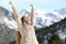 Excited woman raising arms in the snowy mountain