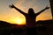 Excited woman raising arms at sunset in nature