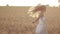 Excited woman spinning in wheat field at sunset