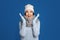 Excited woman wearing sweater, gloves, scarf and hat on blue background. Winter season