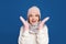 Excited woman wearing warm sweater, gloves, scarf and hat on blue background. Winter season