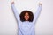 Excited young african american woman cheering with hands raised against white background