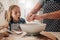 Excited young girl with mother preparing dough