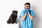 Excited young male doctor veterinarian admiring cute pet sitting on table. Cute black pug dog waiting for examination at