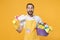 Excited young man househusband in apron rubber gloves hold basin with detergent bottles washing cleansers doing