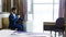 Excited young man in suit drinking coffee in hotel room