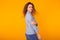 Excited young woman with curly hair in blue home wear, widely smiling having fun. Isolated on yellow background. Copy