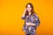 Excited young woman with curly hair in home wear pajama, widely smiling having fun. Isolated on yellow background. Copy