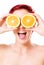 Excited young woman holding oranges over her eyes