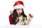 Excited young woman opening a Christmas gift. Cute girl in a Santa Claus costume unleashes a ribbon on a new year gift lying on