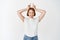 Excited young woman showing tongue and horns sign, winking happy at camera, standing in casual t-shirt and jeans on