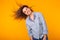 Excited young woman waving hair in blue home wear, widely smiling having fun. Isolated on yellow background.