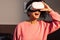 Exciting young woman in casuals wearing VR goggles indoors