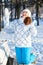 Exciting young woman with hands up standing on bench in winter park