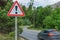 An exclamation mark on a road sign warning of danger and a fast-moving car