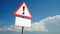 Exclamation mark on a road sign with a white nameplate background sky with clouds