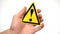 Exclamation mark sign isolated. Male hand showing warning yellow sign