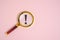 Exclamation mark under magnifying glass, on pink background