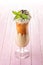 Exclusive coffee cocktail with caramel topping on glass with cream and mint leaf, on white background, frappe