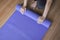 Exercise equipment,Woman hands rolling or folding purple yoga mat after a workout,Healthy fitness and sport concept