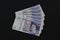 EXETER, ENGLAND - DECEMBER 20TH 2019: A fan of twenty pound Sterling notes rests on a black background