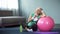 Exhausted active lady wiping with towel after home workout with fitness ball