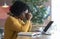 Exhausted african girl sitting in cafe, looking for job online