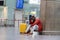 Exhausted African man on a long night connection at airport, waiting for a plane sitting in terminal