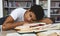 Exhausted afro guy sleeping on books in library